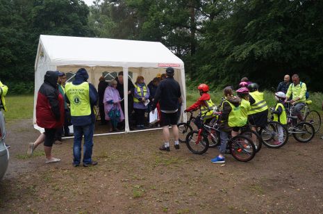 Marshals and early arriving cyclists shelter from the shower